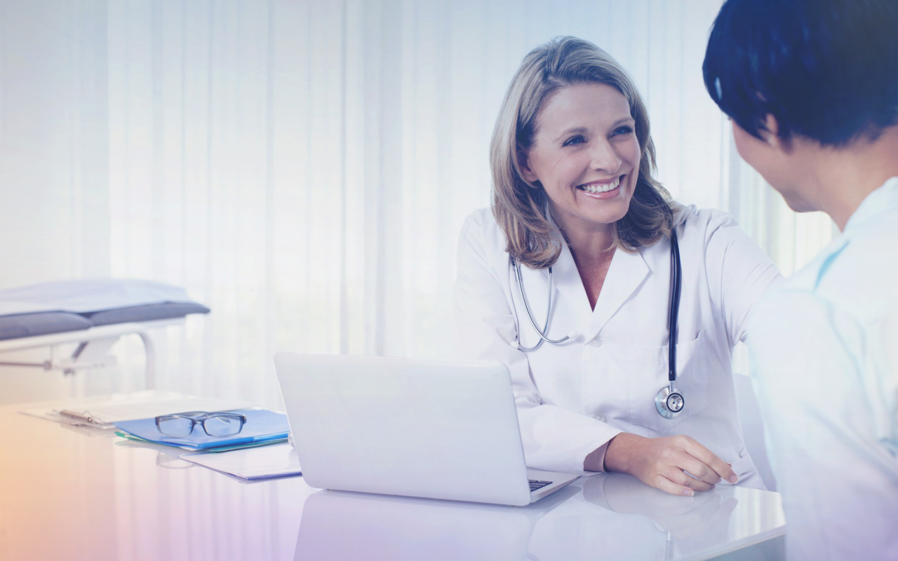 Arvato Systems_Gesundheitswesen_Female doctor with stetoscope smiling at patient Arvato Systems_Gesundheitswesen_Female doctor with stetoscope smiling at patient